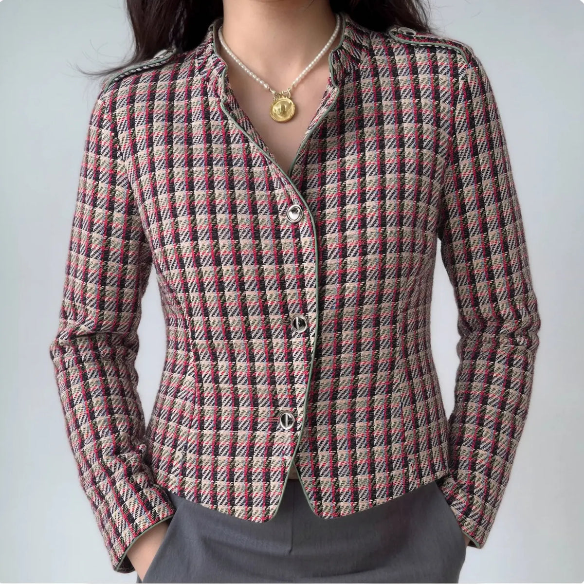 Model wearing plaid tweed stand collar jacket with pearl necklace and gray trousers
