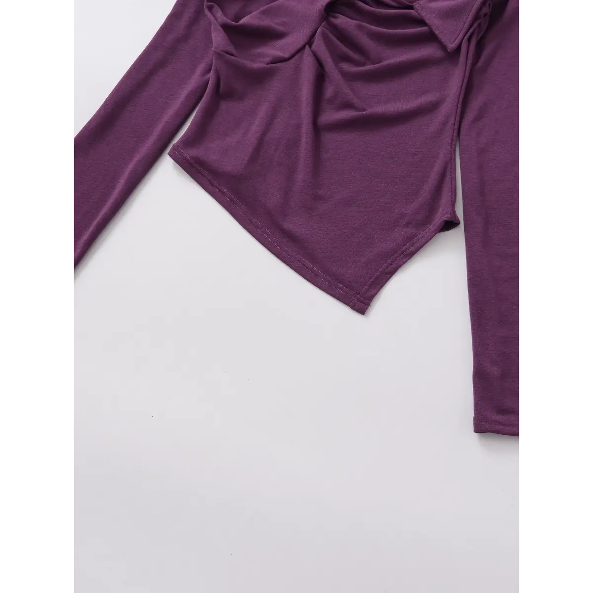 Close-up of the hem on the purple twist-front top, showing the asymmetric cut and stretchy knit texture
