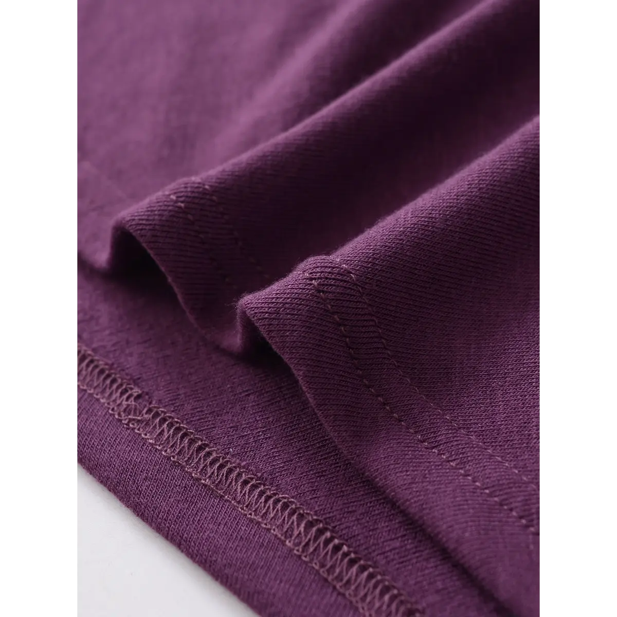 Close-up of the seam on the purple twist-front top, showing the stretchy knit fabric and neat stitching