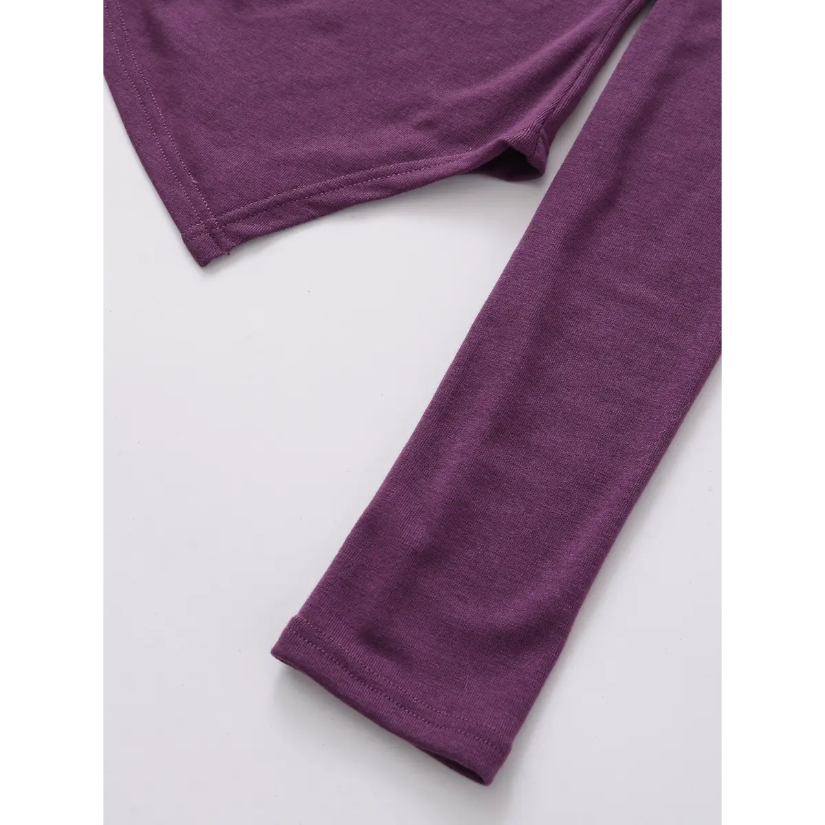 Close-up of the sleeves on the purple twist-front top, showing the smooth knit fabric and clean finished hems