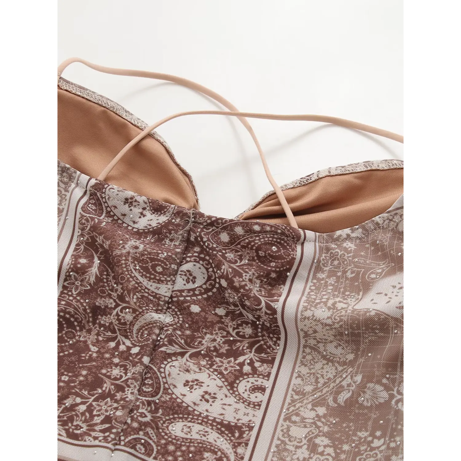 Bust partial close-up sweetheart twist gathered neckline, two large gold sphere bead hardware keyhole cutout, ultra thin nude crisscross spaghetti straps, sheer mesh brown paisley bandana print with micro rhinestones
