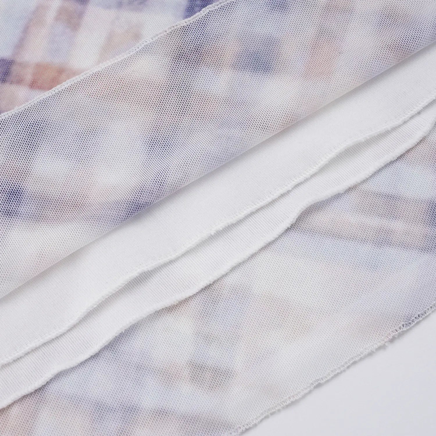 Flat layered close shot showing dual mesh construction: sheer printed plaid outer fabric and soft solid white lining, showcasing lightweight thin drape and layered opacity
