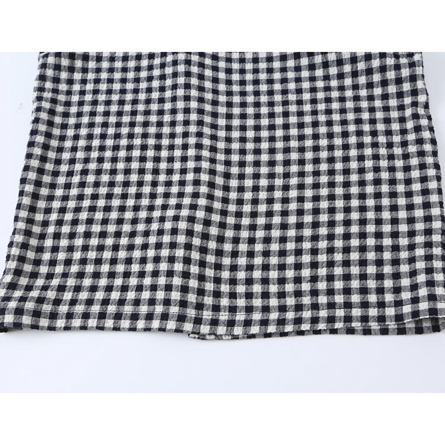 Bottom skirt hem flat close-up, crinkle bubble woven texture, neat straight hem stitching, small gingham grid print