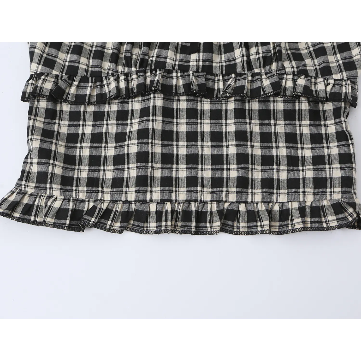 Wide shot of tiered ruffle waist panel on black white check crop top, double frill layered design, soft plaid woven fabric texture