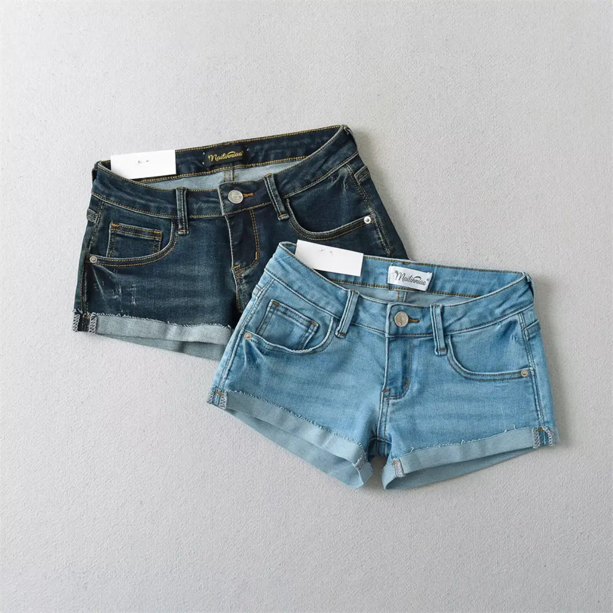 Two-tone view of light blue and dark wash low-rise denim shorts laid flat.