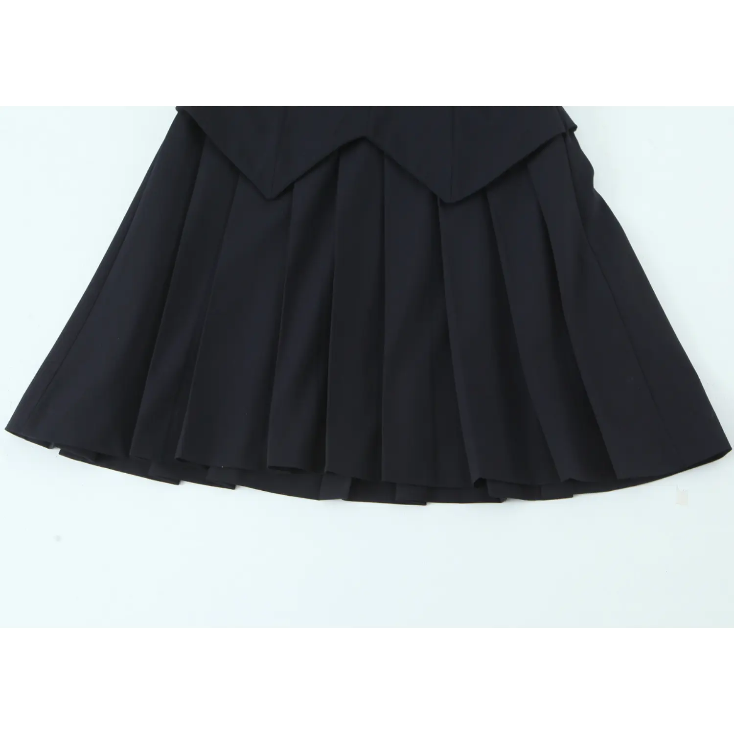 Lower skirt full shot, evenly spaced sharp box pleats, thick woven fabric holds pleat shape permanently, straight mini hem