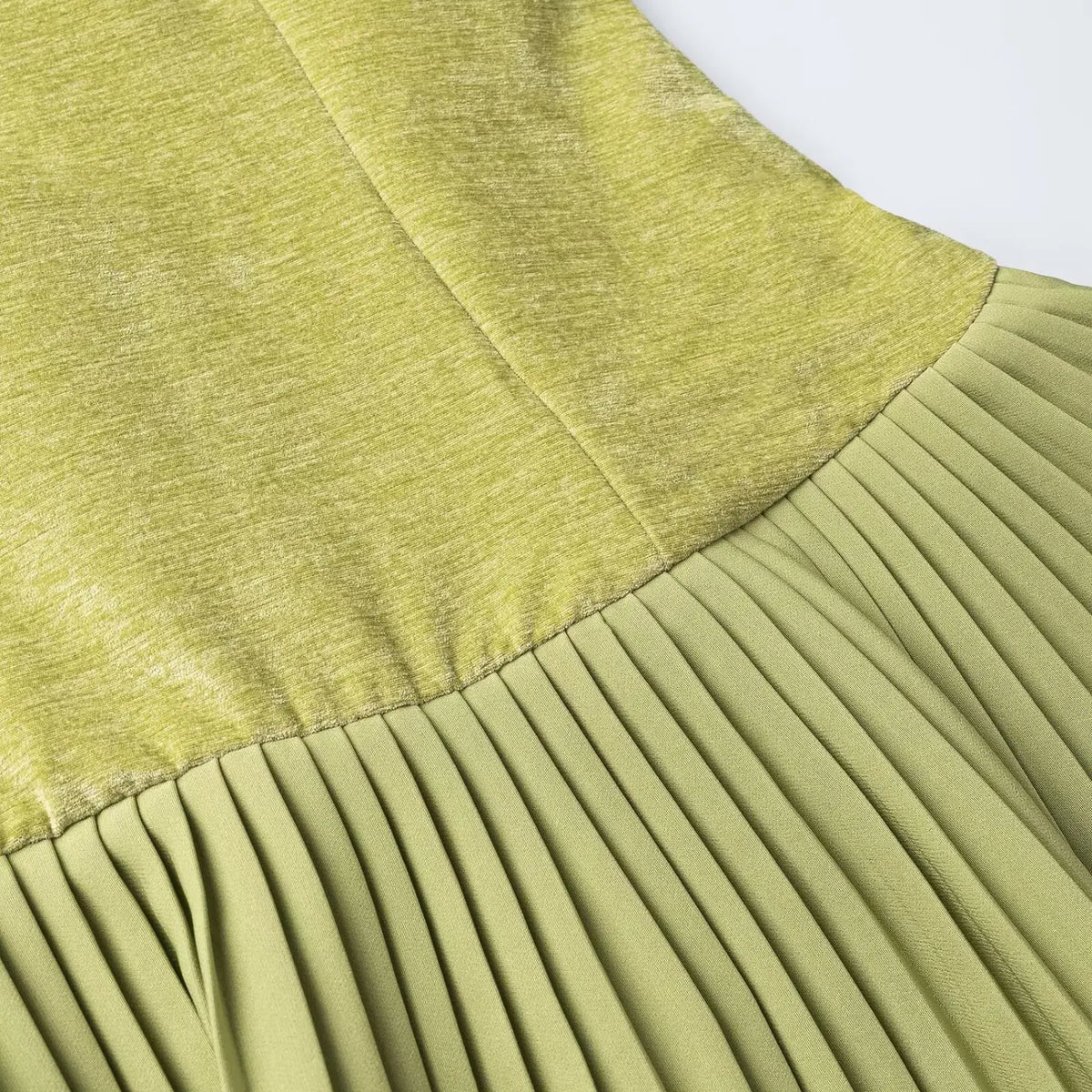 Close-up of green velvet top and pleated skirt seam