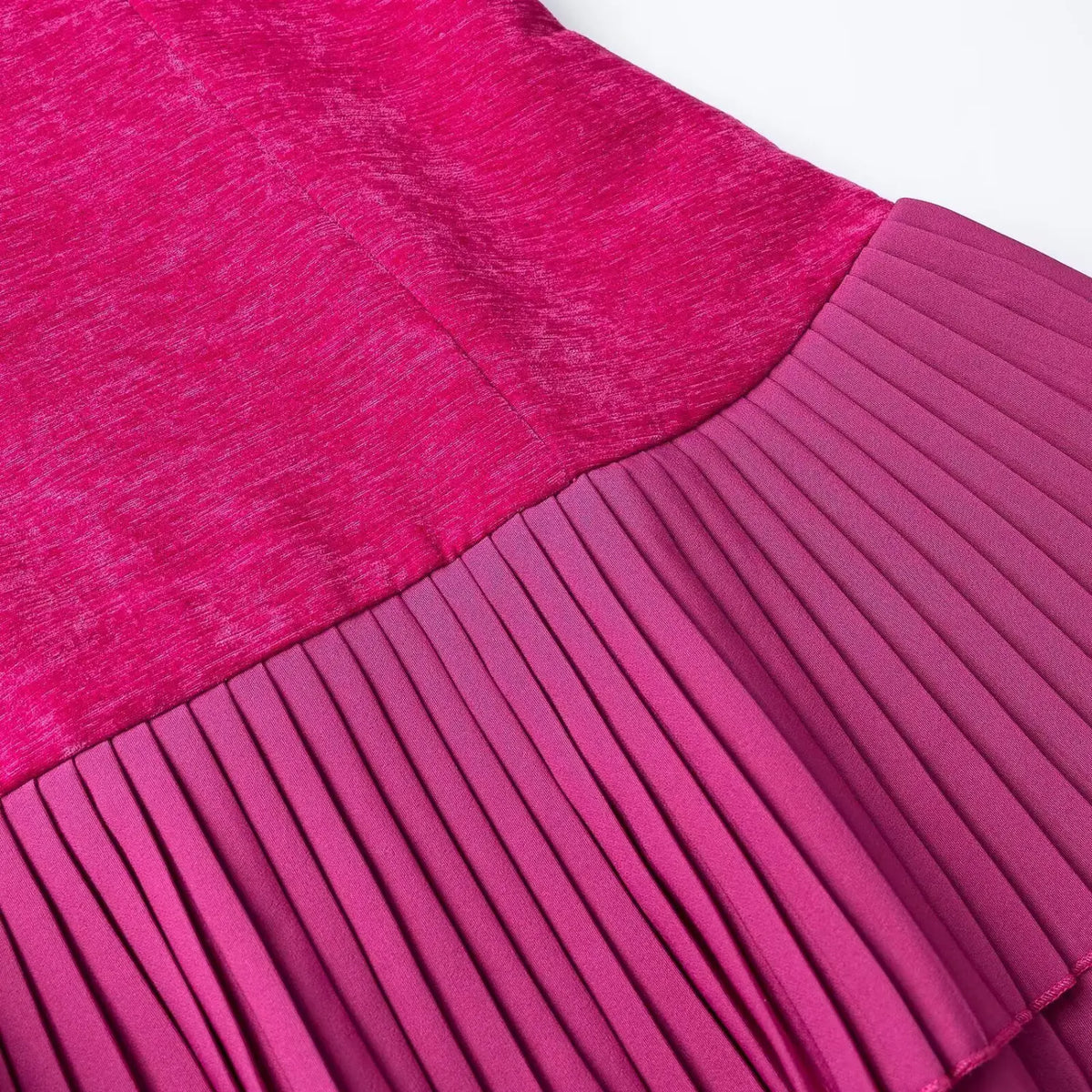 Close-up of fuchsia velvet top and pleated skirt seam