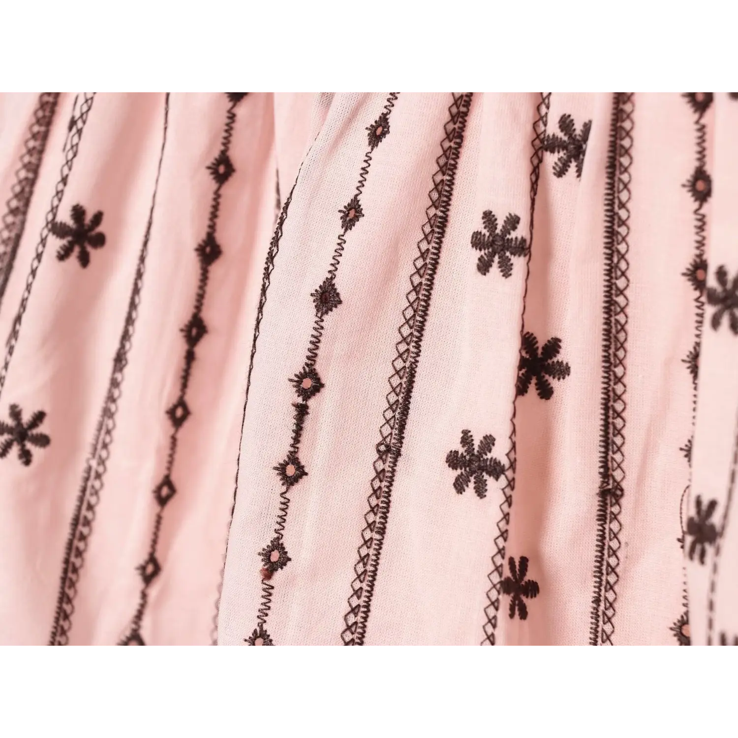 Flat fabric closeup, vertical line stitching with scattered tiny flower embroidery