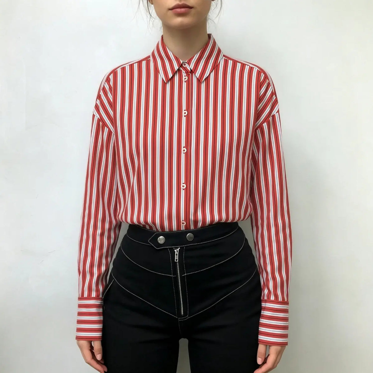 Model wearing red vertical stripe button down shirt with black high-waisted trousers