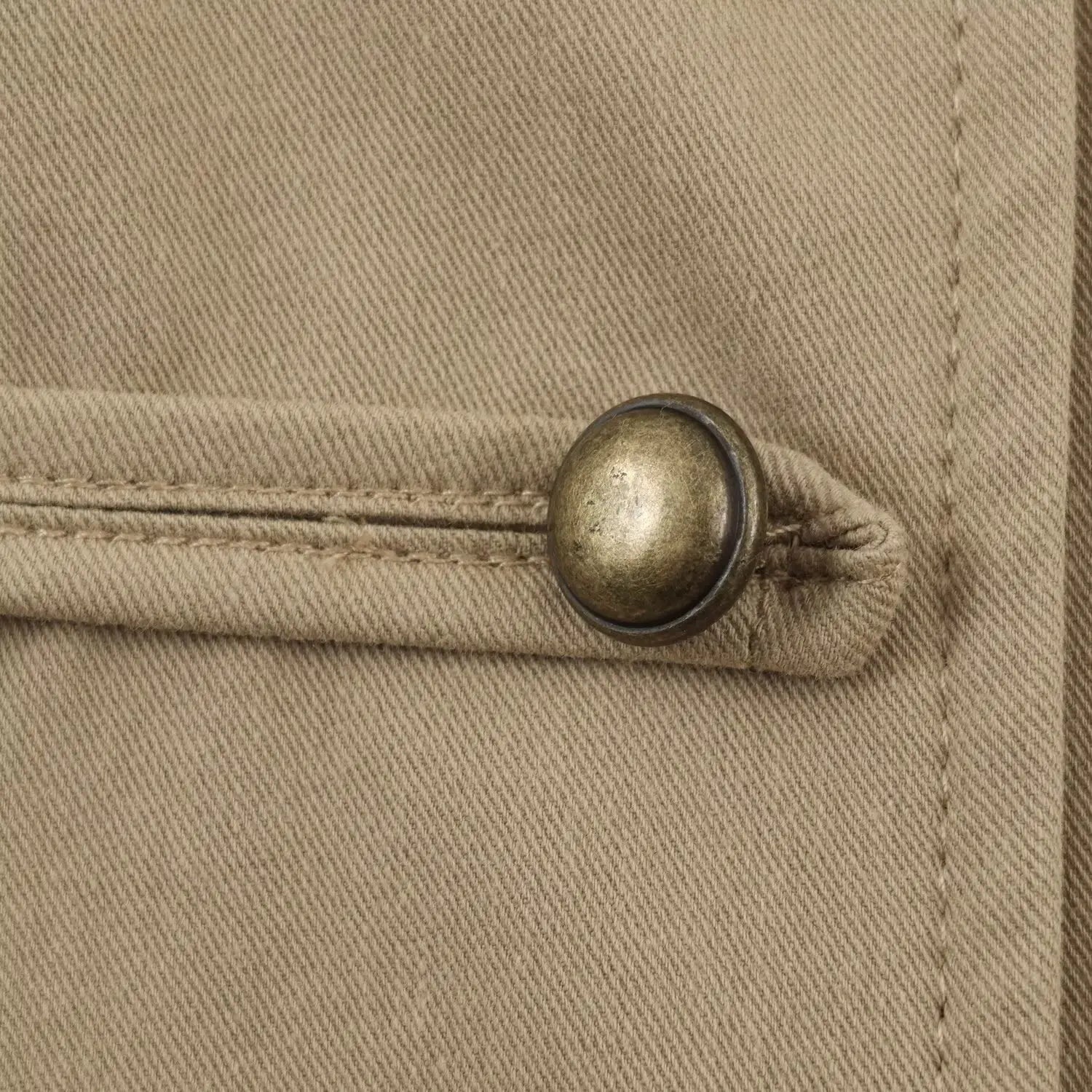 Macro close-up of vintage antique brass round metal button with stitched fabric tab detail