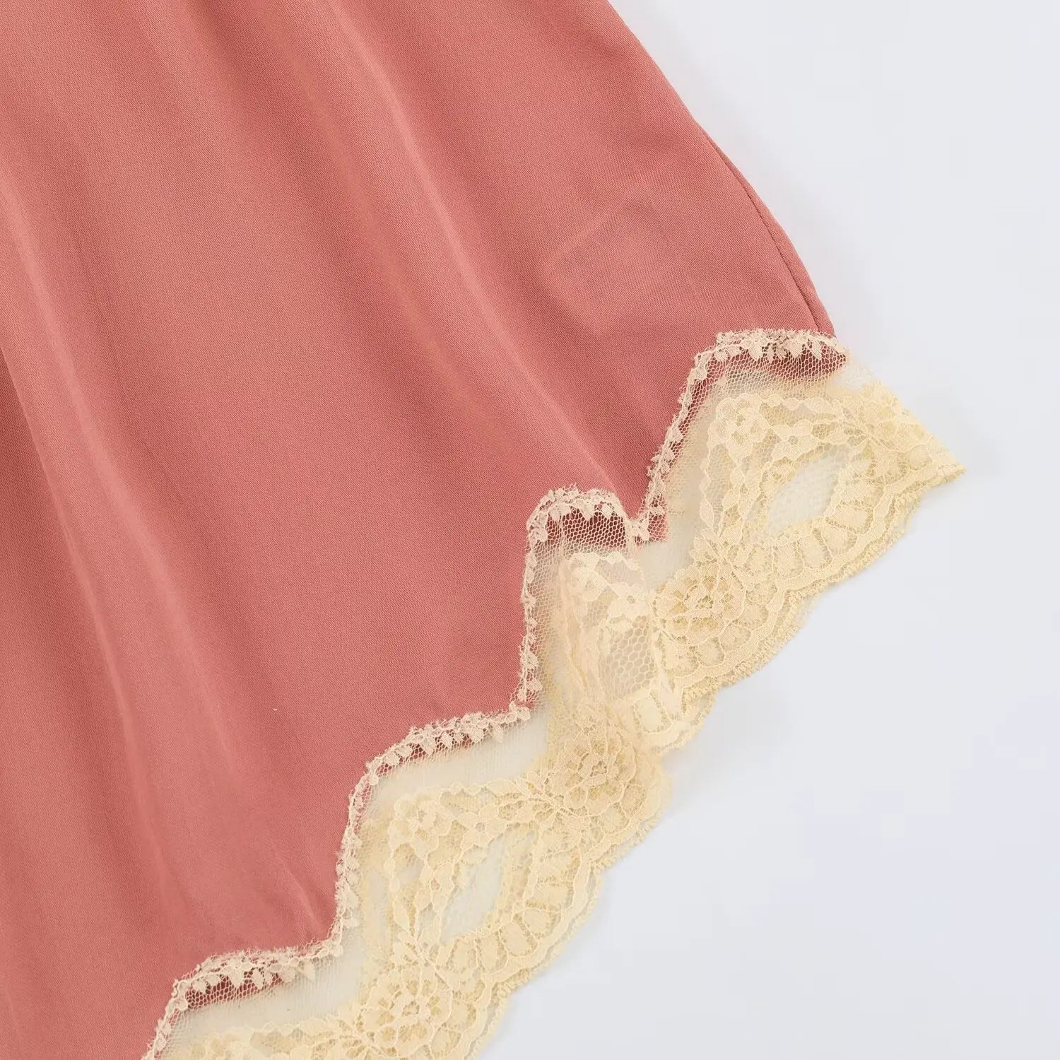 Detail view of scalloped floral lace edging on camisole uneven hem