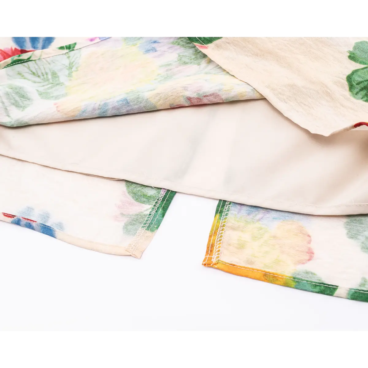 Close-up of dress hem, showing outer floral fabric and solid inner lining with neat overlock stitching.