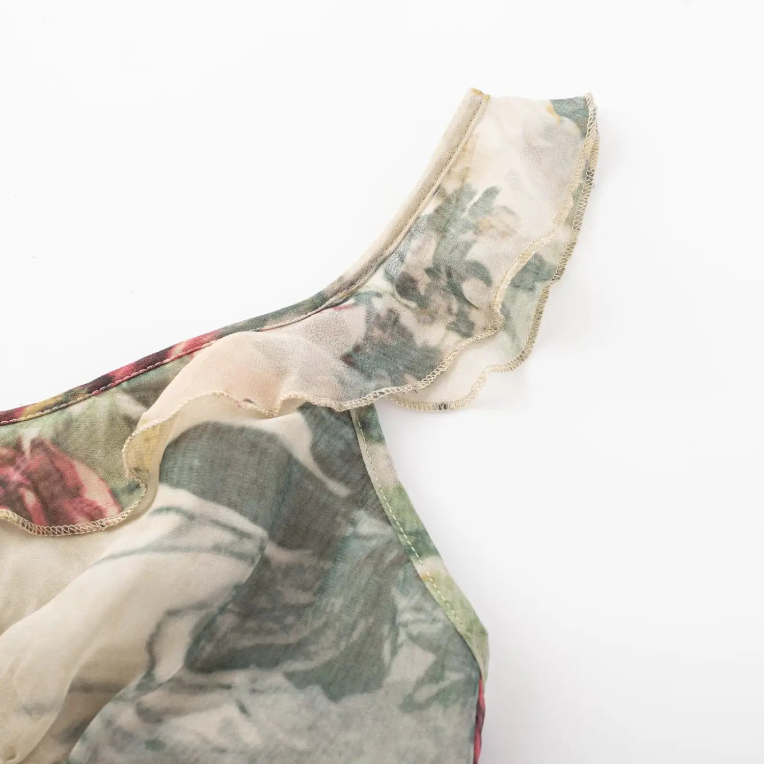 Extreme close‑up of ruffle shoulder strap edge, fine stitching and floral mesh fabric texture