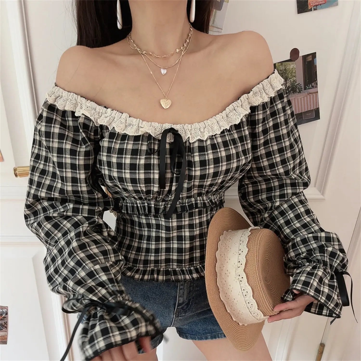Vintage black white gingham off shoulder crop top other angle model shot, highlight cold shoulder lace trim front drawstring waist cinched cropped silhouette straw hat & denim shorts casual date outfit display