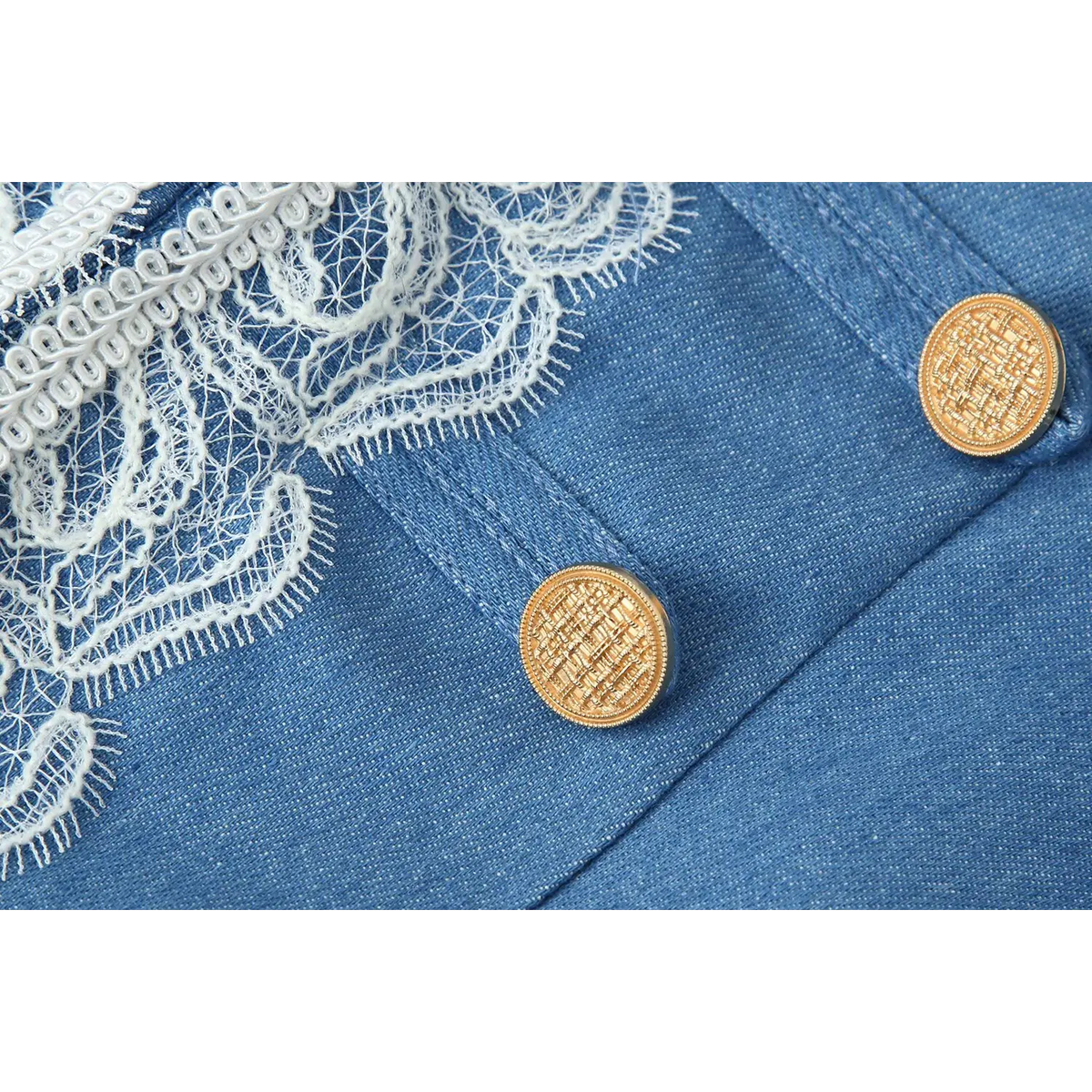 Close-up of antique gold embossed button and delicate white eyelash lace on blue military jacket