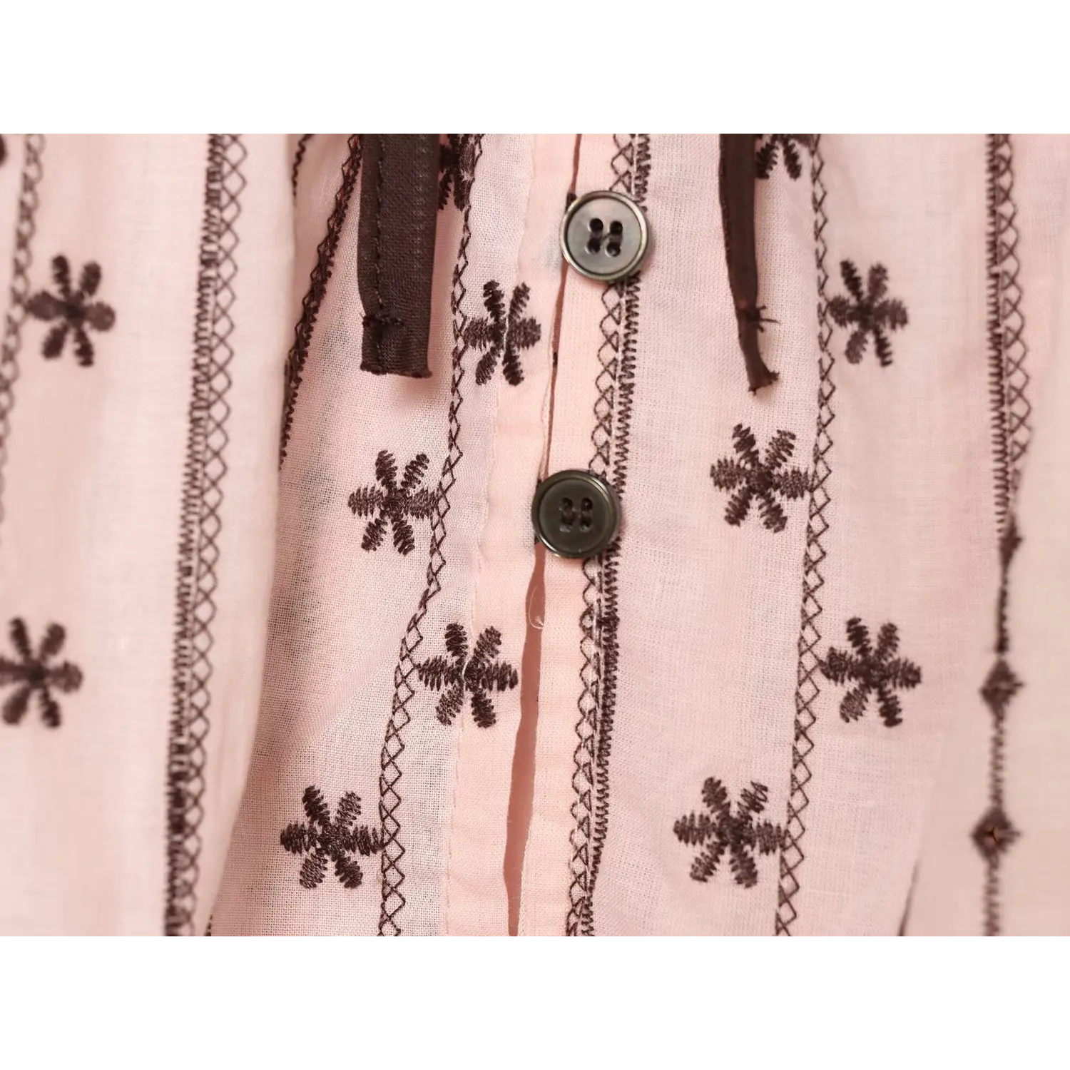 Macro shot of antique tone four-hole metal buttons on front placket