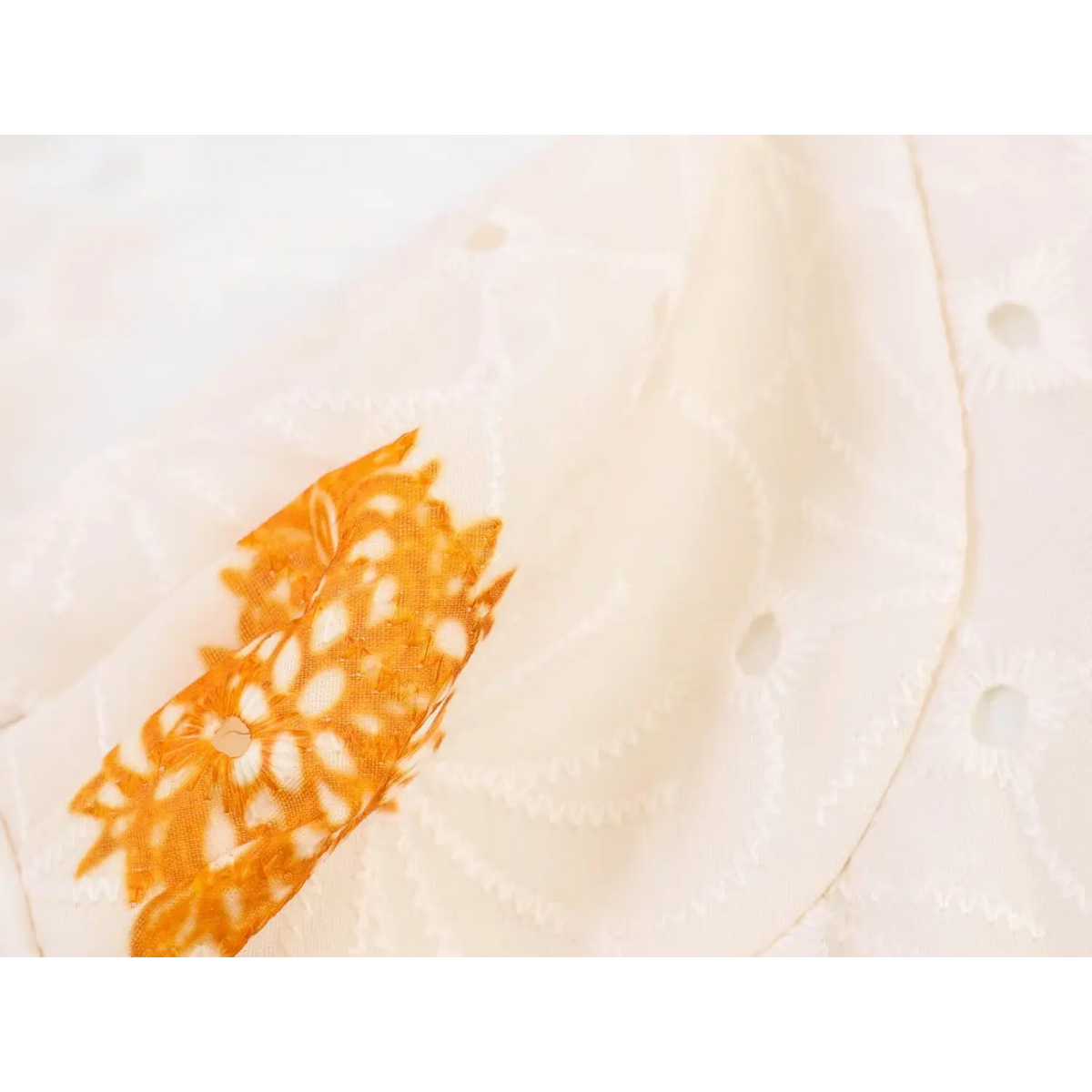 Close-up of retro orange ethnic paisley print pattern on cream base maxi dress