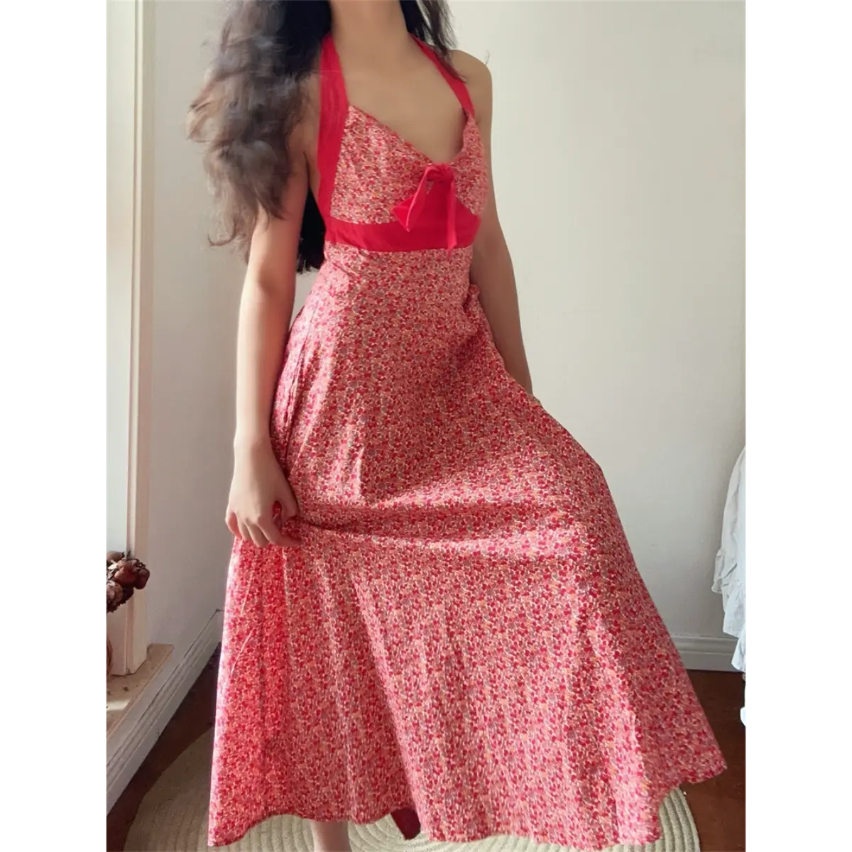  Front lifestyle shot of model wearing red cherry print halter maxi dress with solid red bust bow, flowy A-line skirt for retro summer look.