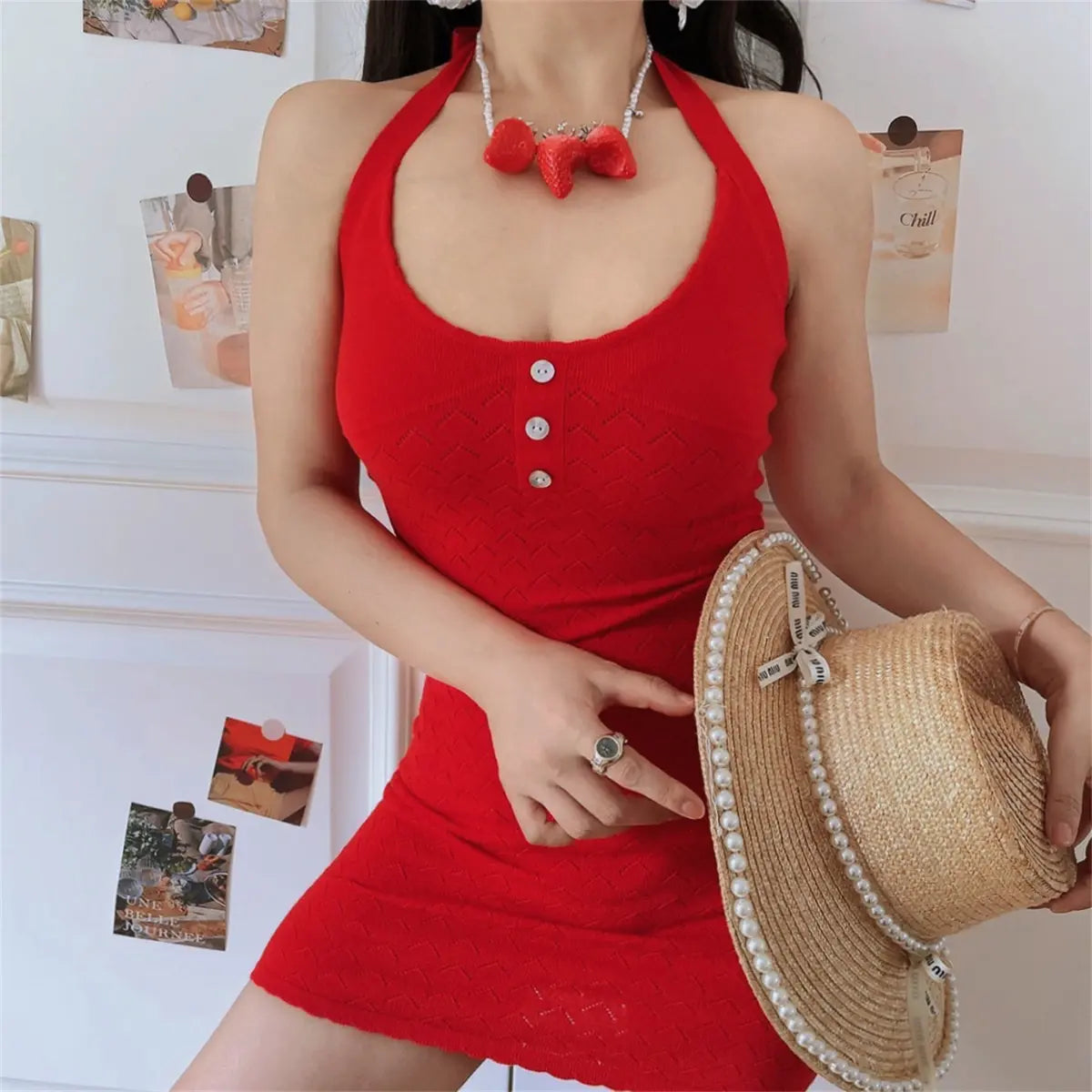  Indoor casual lifestyle picture of bright red textured knit halter mini dress, hand holding pearl straw sunhat for seaside dating look.