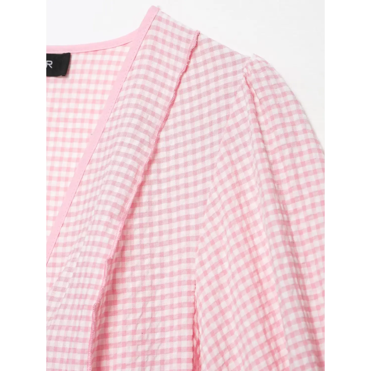 V-neck inner edge close-up, fine raw seam detail, light pink white gingham crinkle woven texture