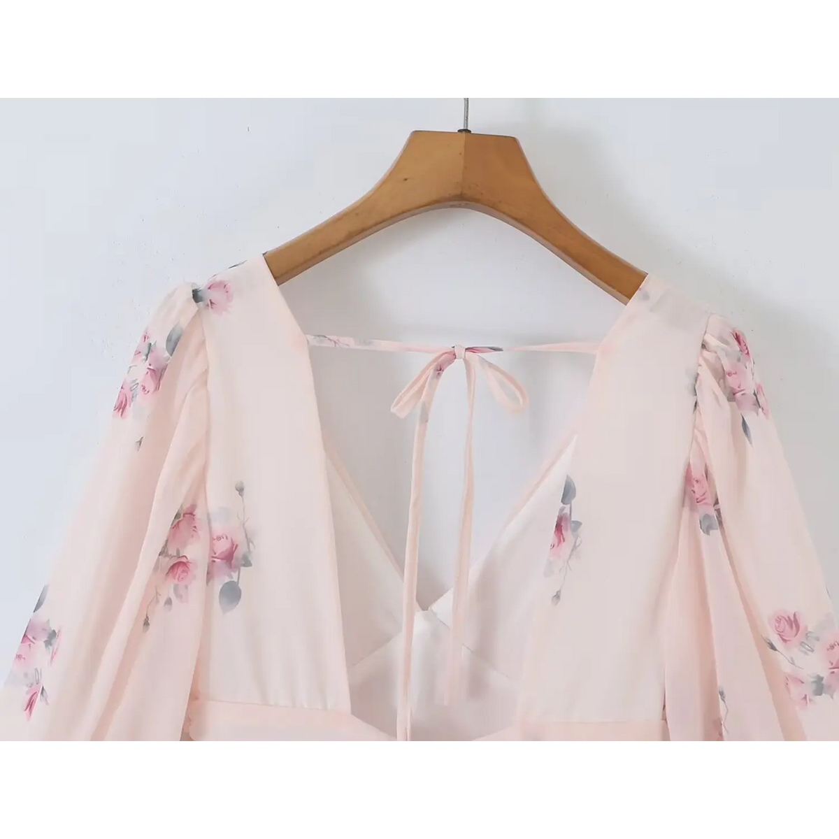 Hanging shot showing deep v front and delicate self tie strap at open back, allover pink rose print