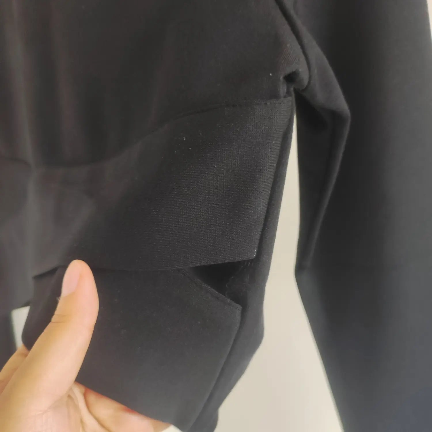 Close-up stitching side cutout and wrap panel of black crop blouse