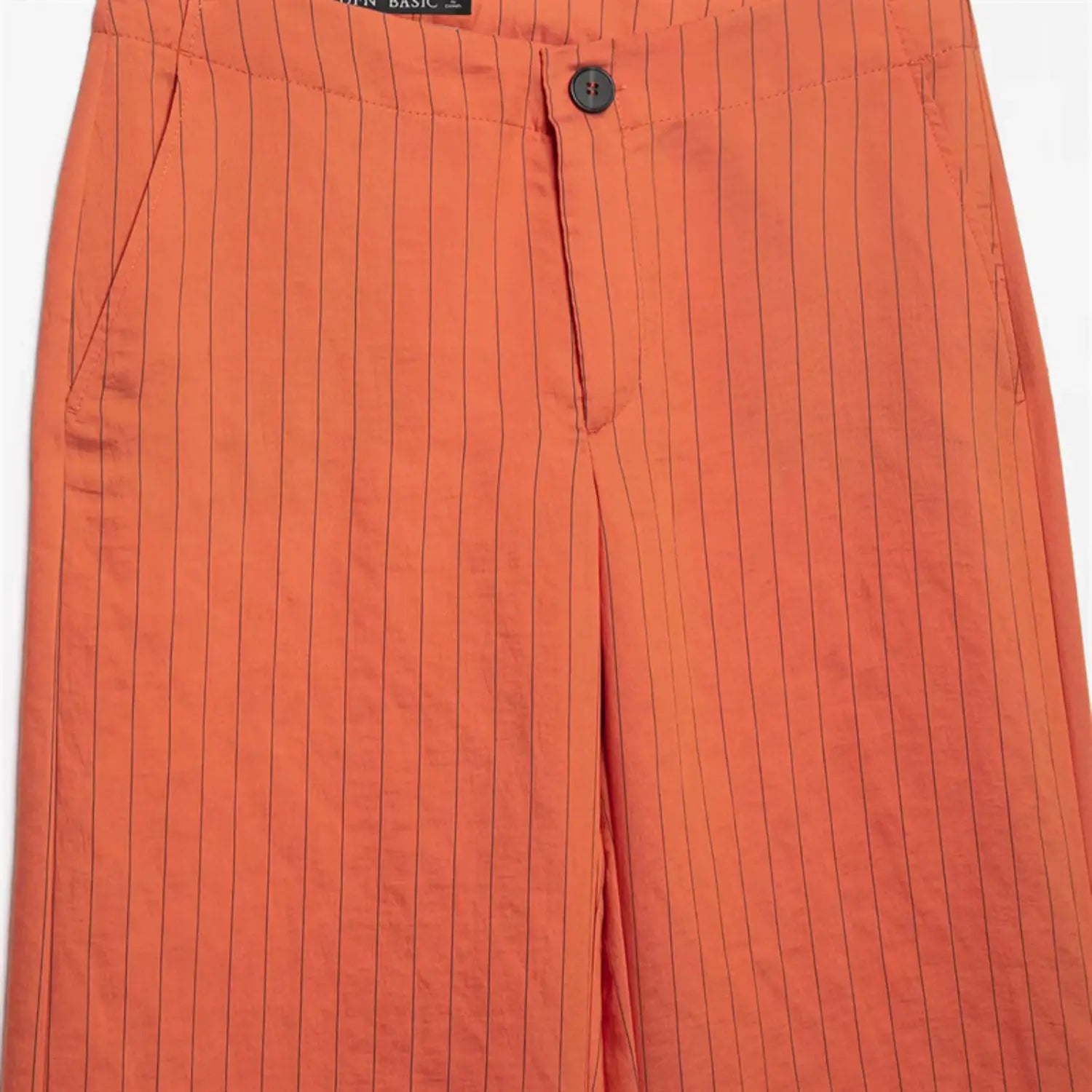 Upper waist close-up, round dark waist button, zipper fly detail, front slash pocket seam, woven pinstripe fabric texture