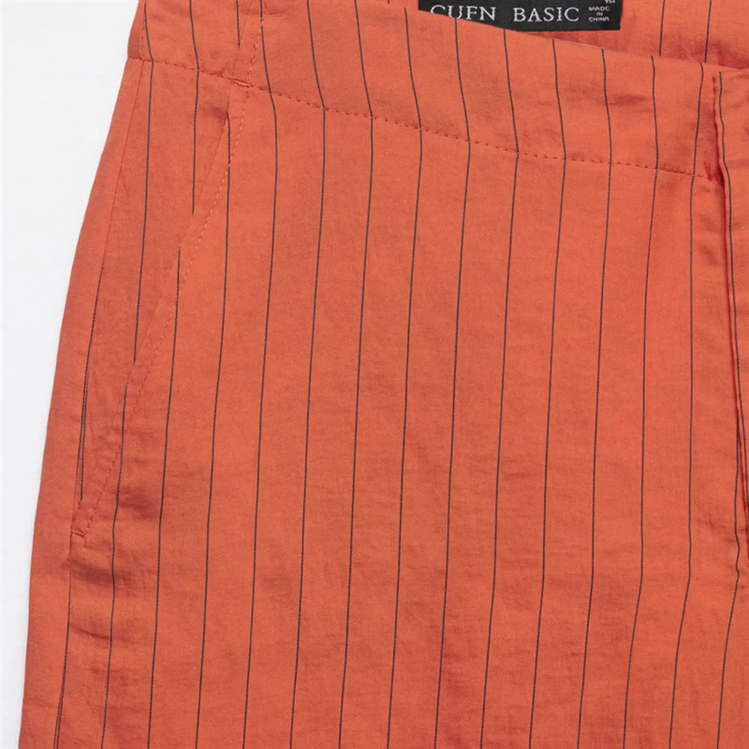 Inner waistband close-up, woven brand label, side pocket outer stitching, orange base dark stripe fabric