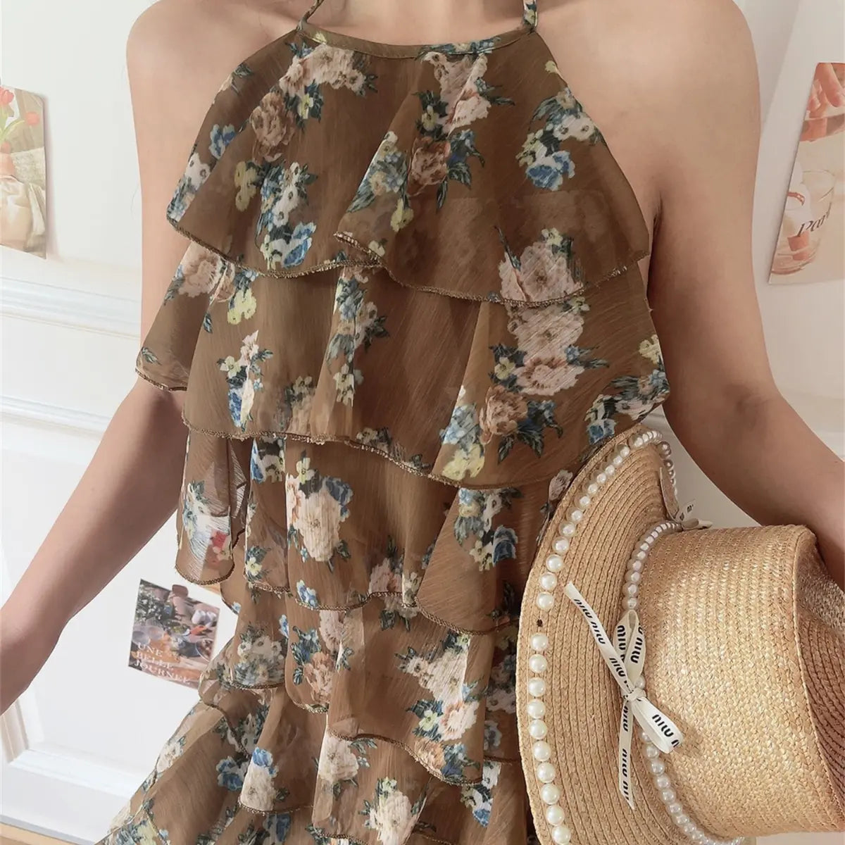 Upper body close lifestyle picture of floral halter cake dress, crinkled sheer chiffon fabric and cascading ruffle tier detail.