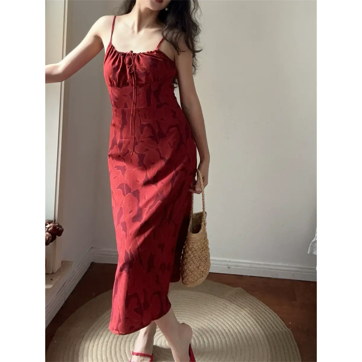 Full body lifestyle photo of rust floral cami midi dress matched with rattan handbag and red slide sandals, retro vacation indoor outfit.