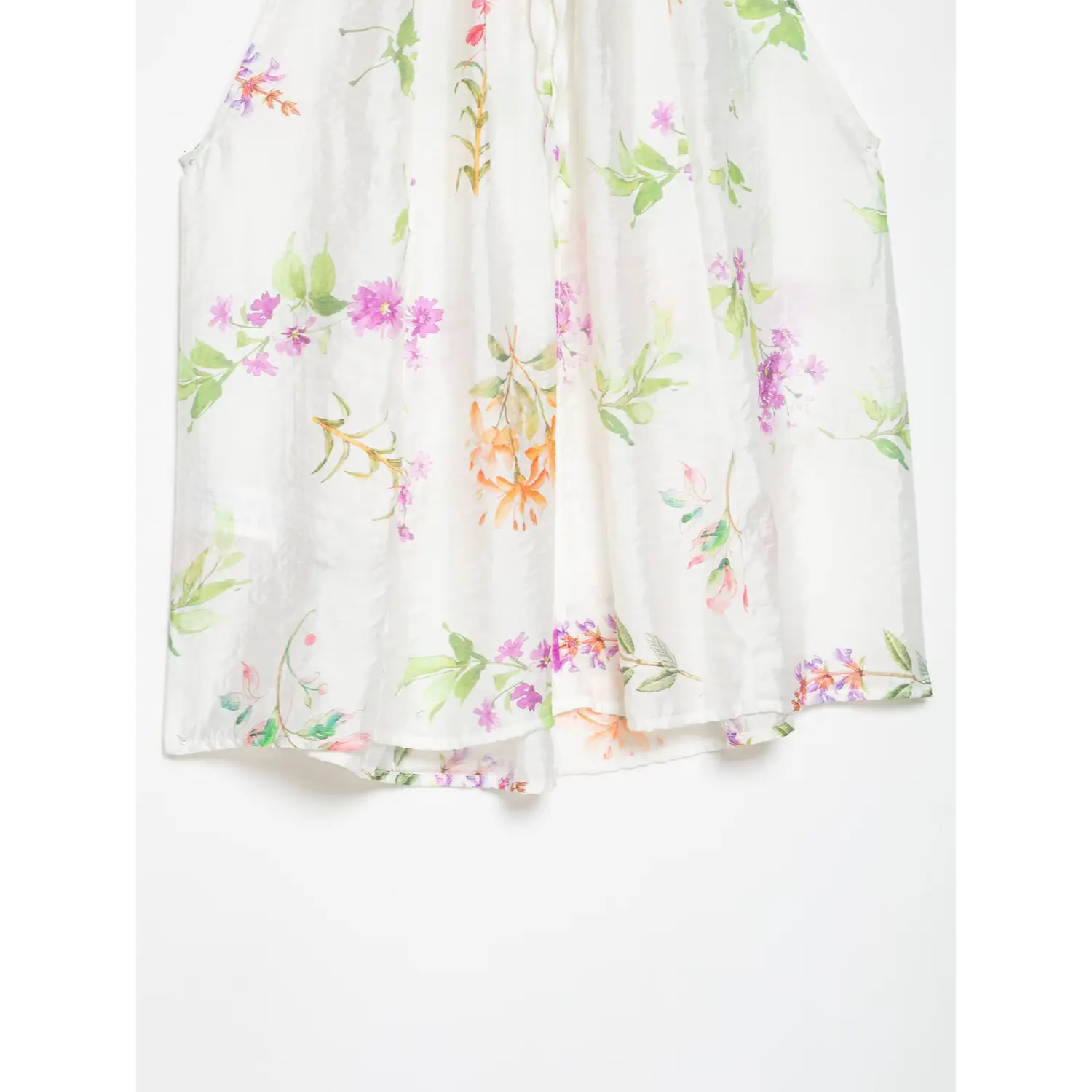 Front flat shot of sleeveless halter top, off-white textured fabric scattered with watercolor peony, clover and orange blossom print, loose flowy hem silhouette