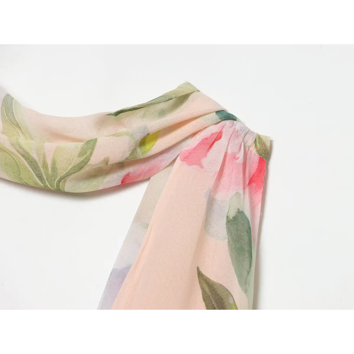 Close-up of the gathered shoulder strap and neckline on a watercolor floral halter dress, showing the fabric texture and print details.
