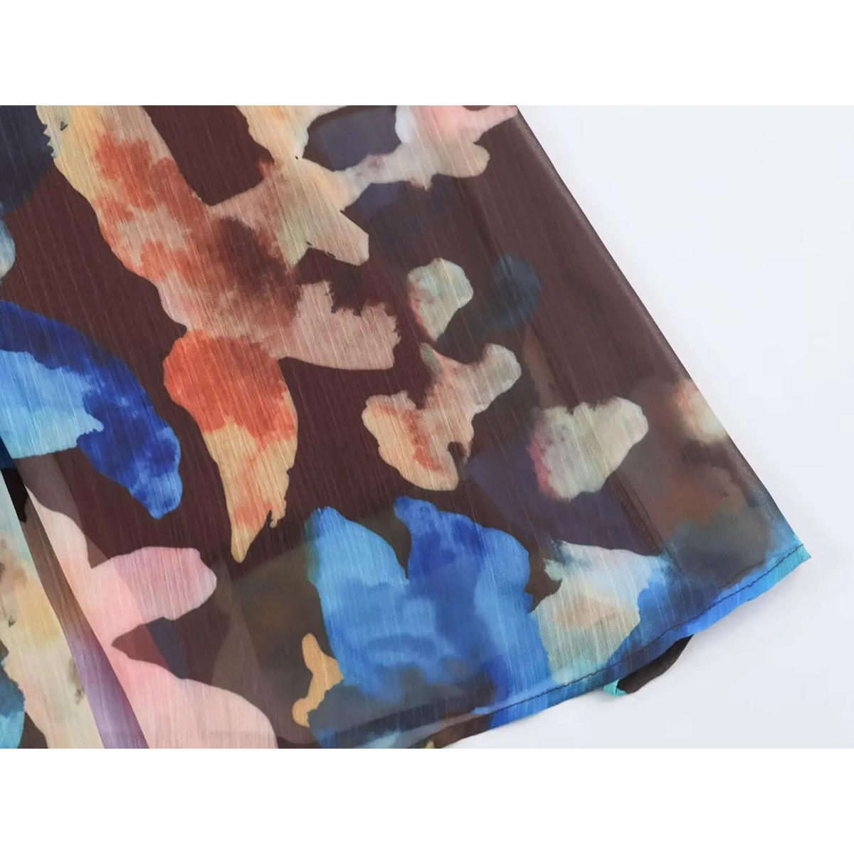 Close-up of hem fabric on watercolor floral print chiffon maxi dress, brown base with blue and orange abstract flower pattern
