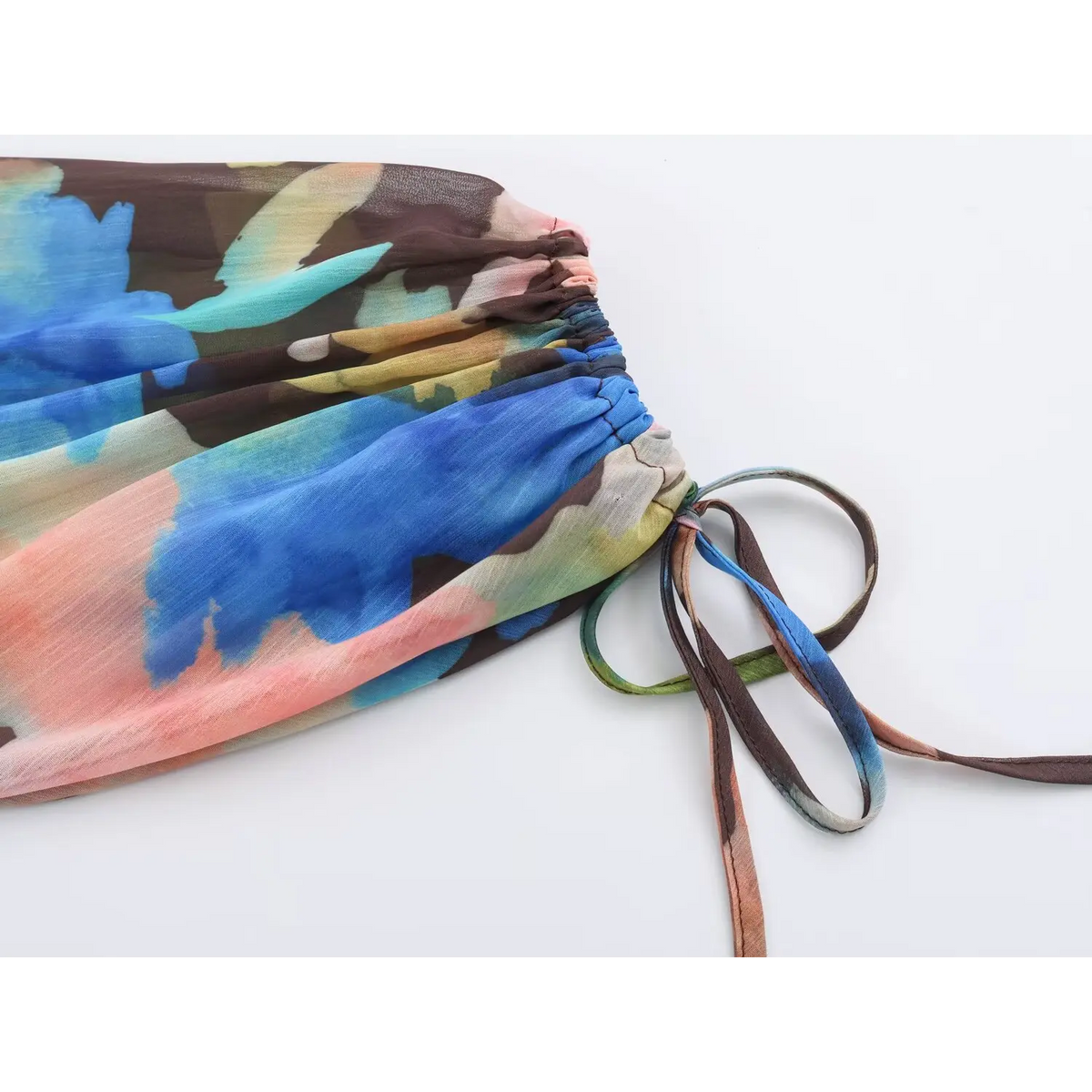 Close-up of flowing long skirt hem, multicolor watercolor print and pleated chiffon texture