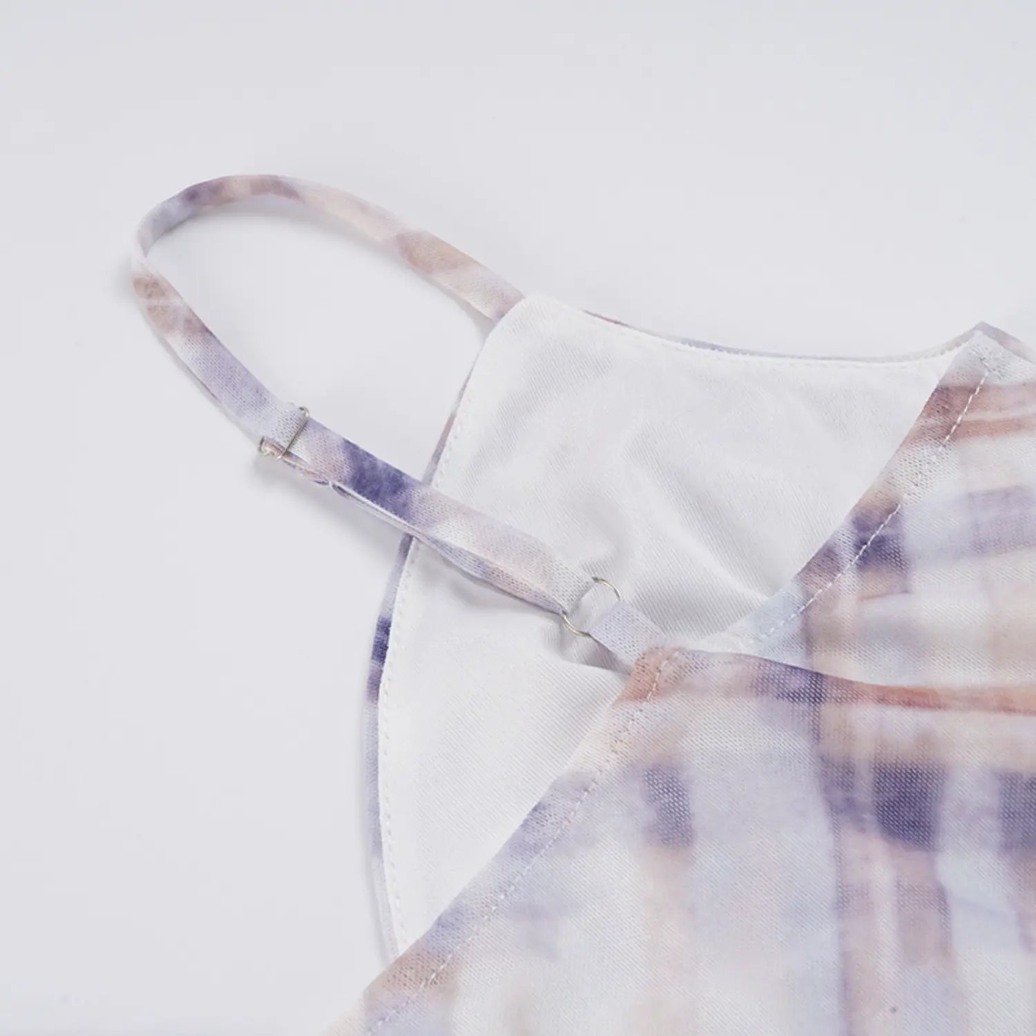 Top-down partial close texture shot of slip dress V-neck construction, matching plaid adjustable slider thin straps, neat stitching connecting mesh outer layer to solid white lining