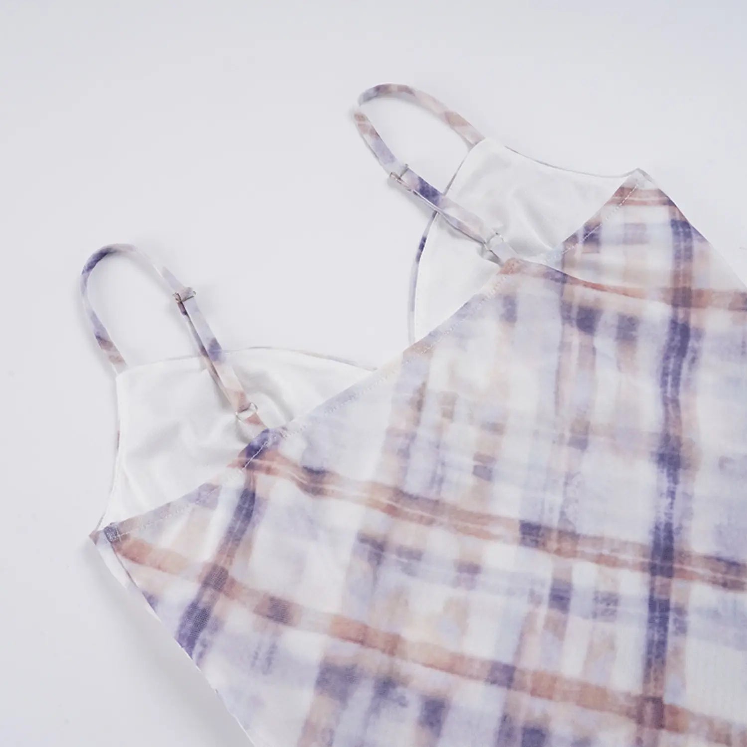 Partial flat back shot of slip dress inner lining and straps, dual metal slider adjustable thin plaid straps, clean straight seam attaching mesh outer shell to white lining