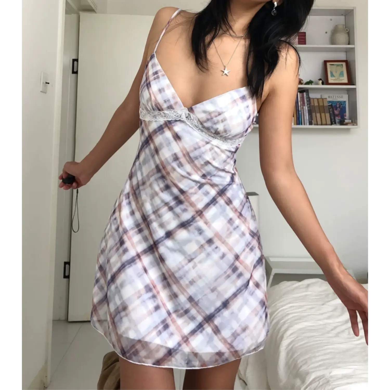Full body indoor bedroom casual shot of lightweight mesh slip mini dress, model spreading arms naturally, soft blurred diagonal plaid print, scalloped white lace trim under bust