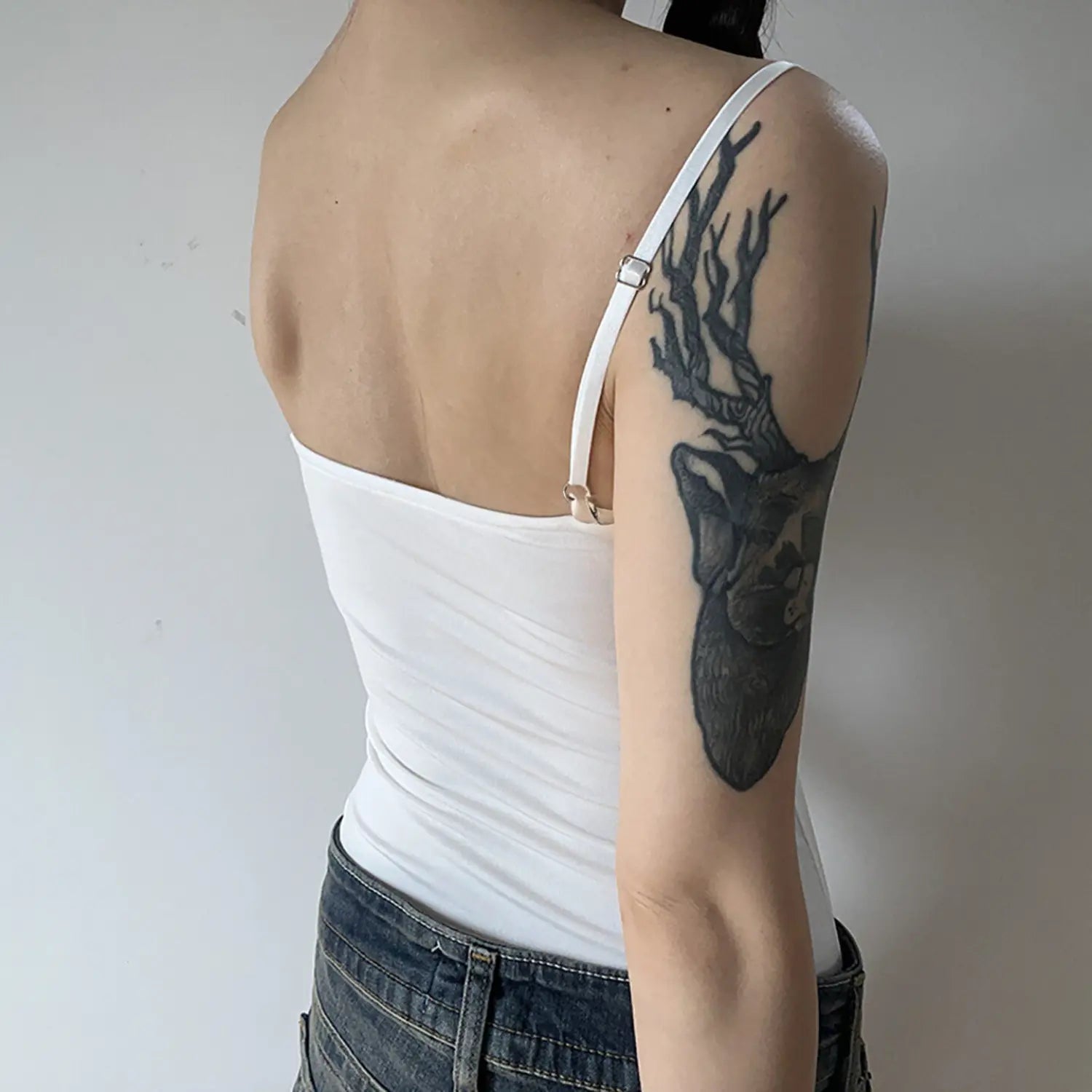 Back detail shot white ribbed camisole tank top, adjustable metal slider spaghetti strap, smooth back slim fitted silhouette with denim jeans
