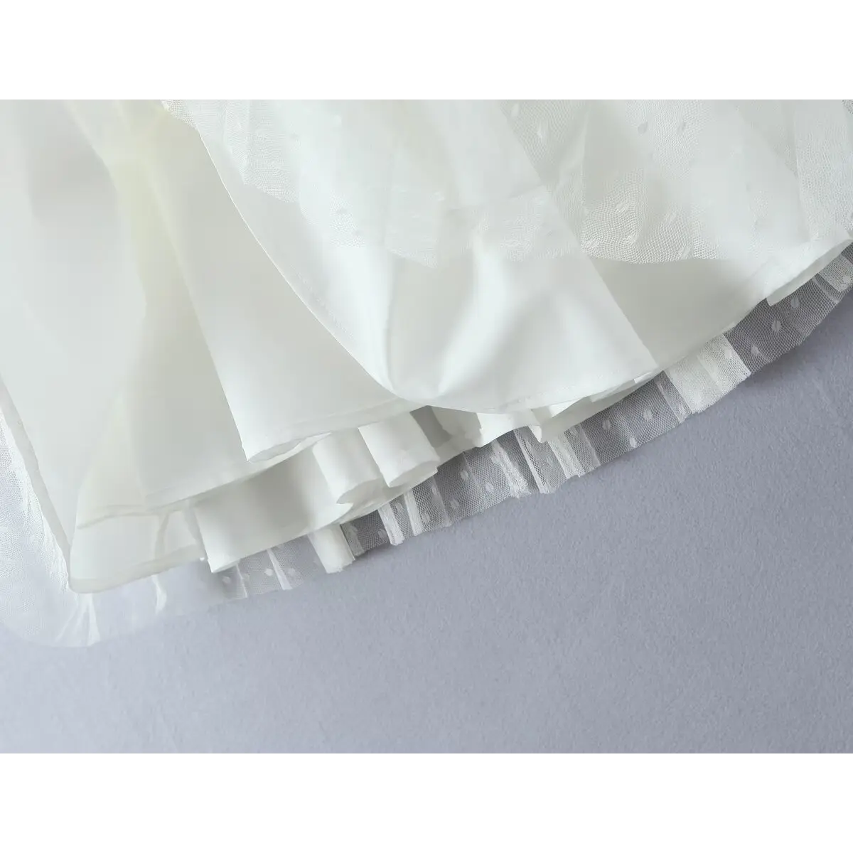 Close-up of layered skirt construction, showing smooth inner lining and dotted mesh overlay.