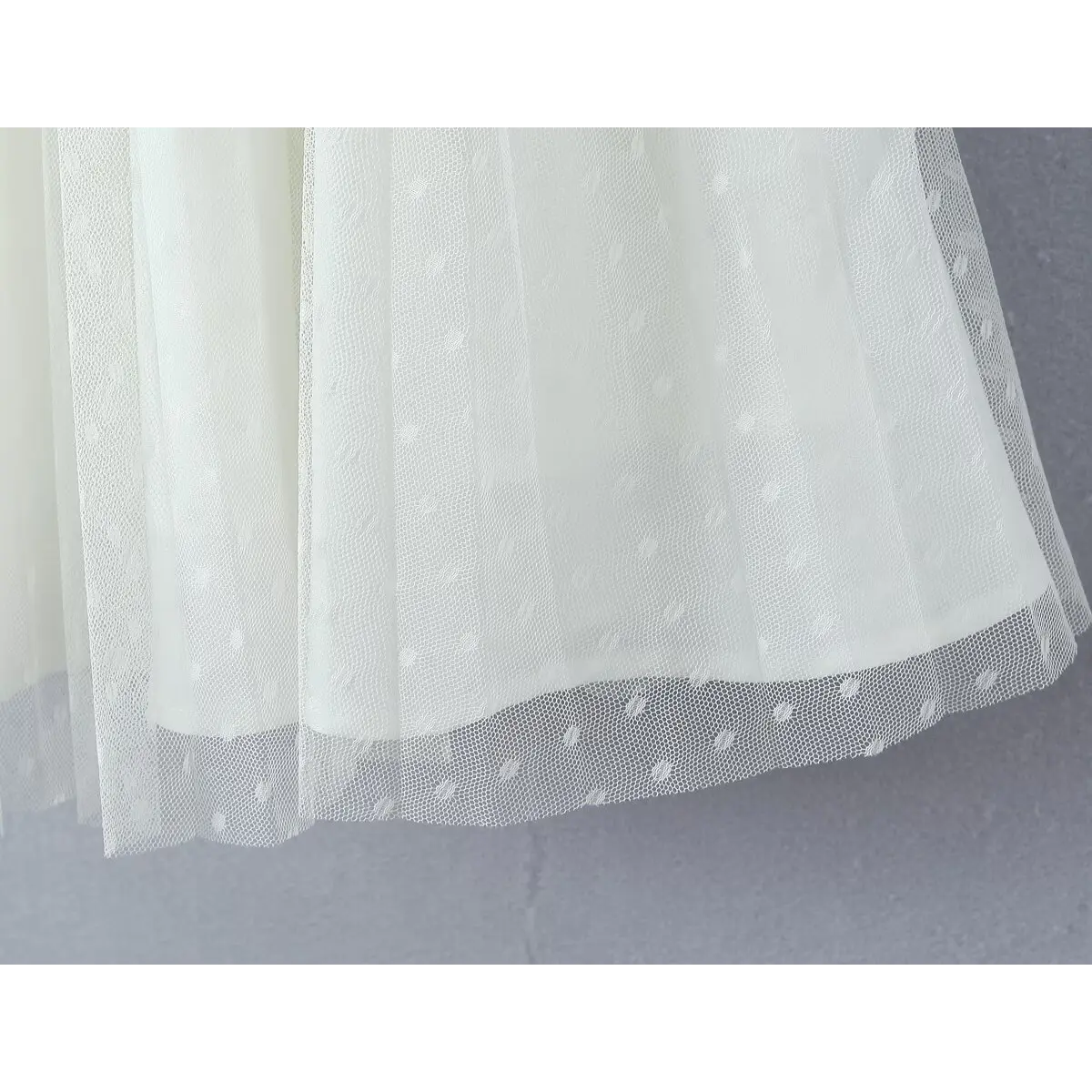 Close-up of flared skirt hem with dotted mesh tulle and finished stitching.