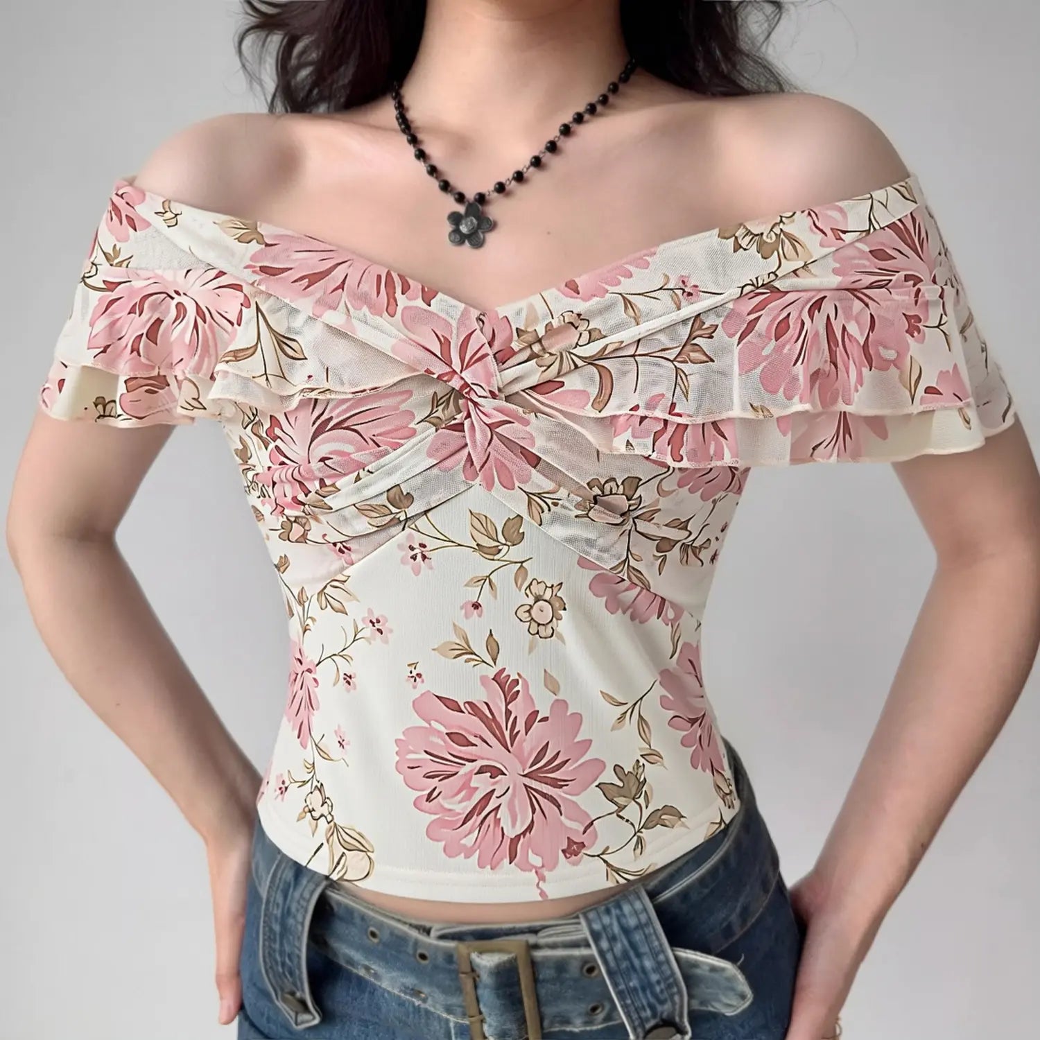 White base pink peony floral mesh off shoulder top half body indoor model shot, off-shoulder ruffle sleeve front twist cropped slim fit matched with denim daily sweet girl outfit display