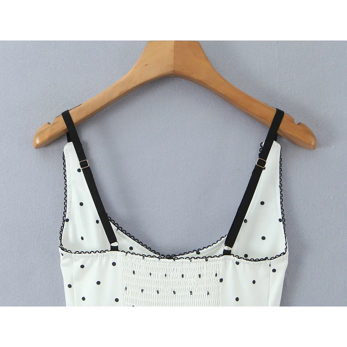 Close-up of the V-neckline and adjustable straps, highlighting the black lace trim and gold sliders.
