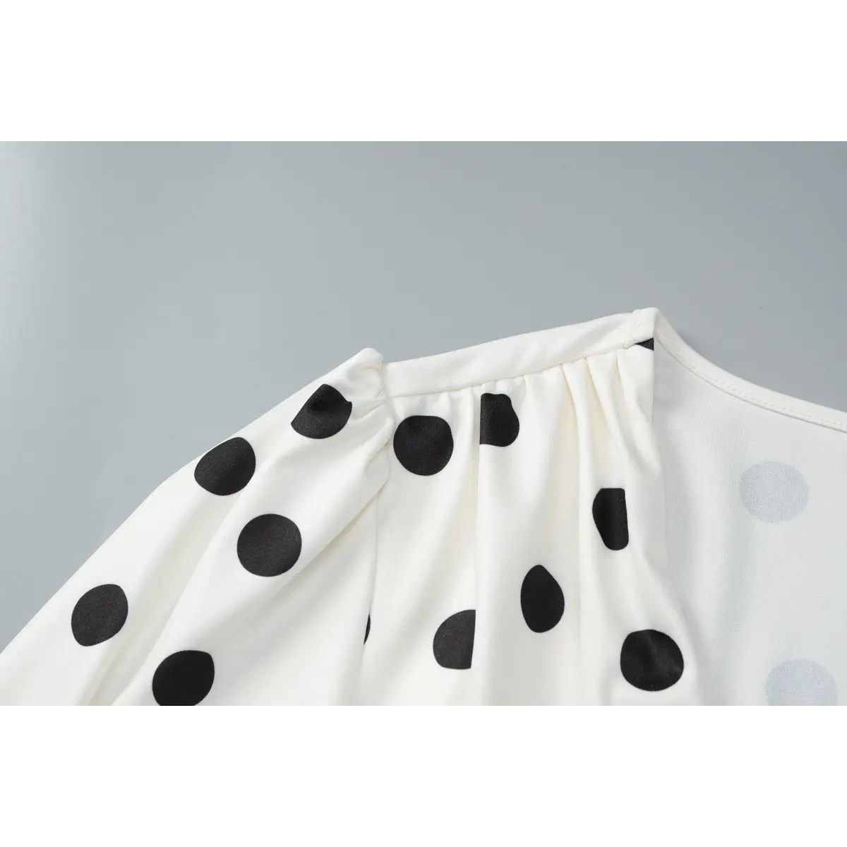 Close-up of the gathered tuck detail at the shoulder, showing the fabric texture and dot print.