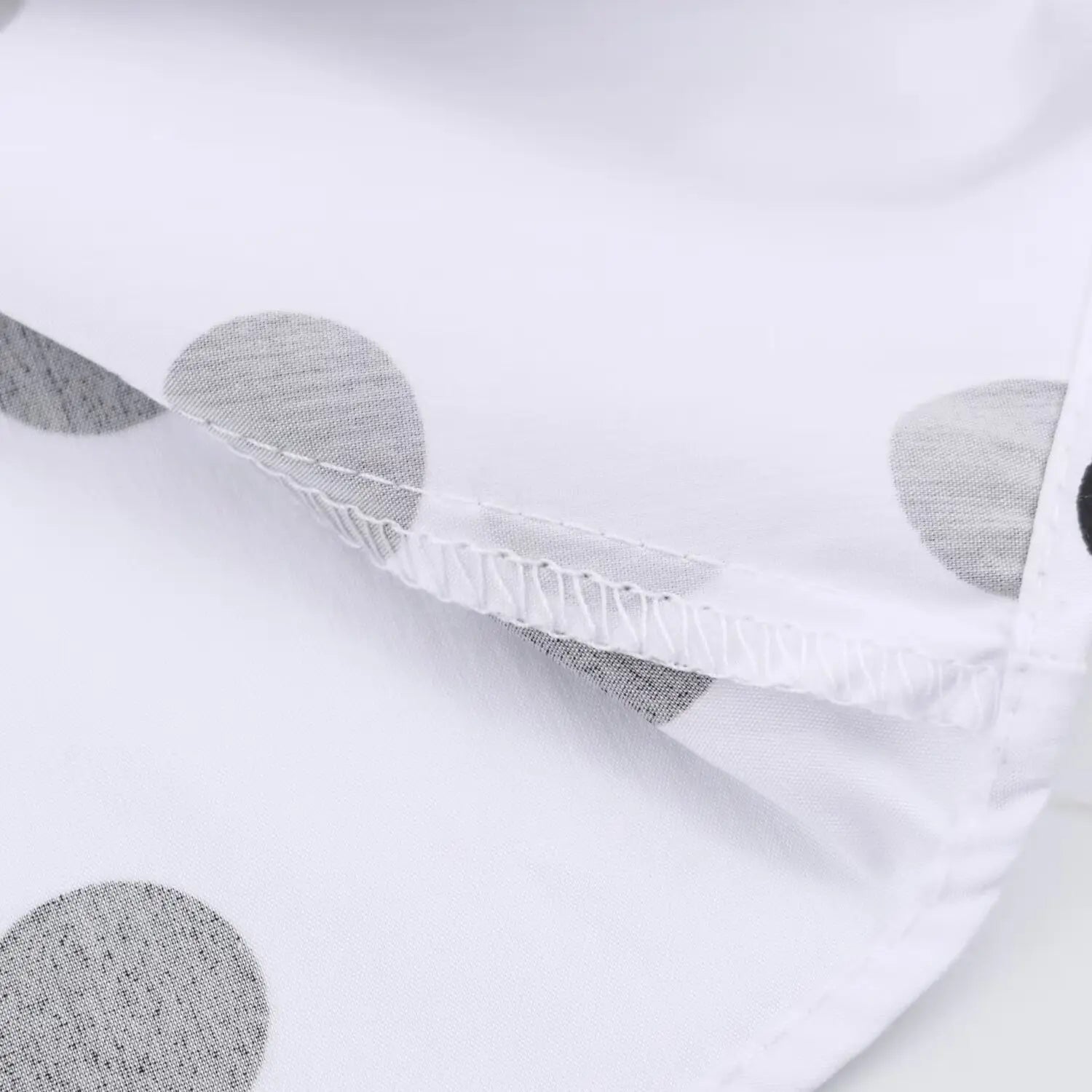 Close‑up overlock stitching at hem of white black polka dot maxi dress