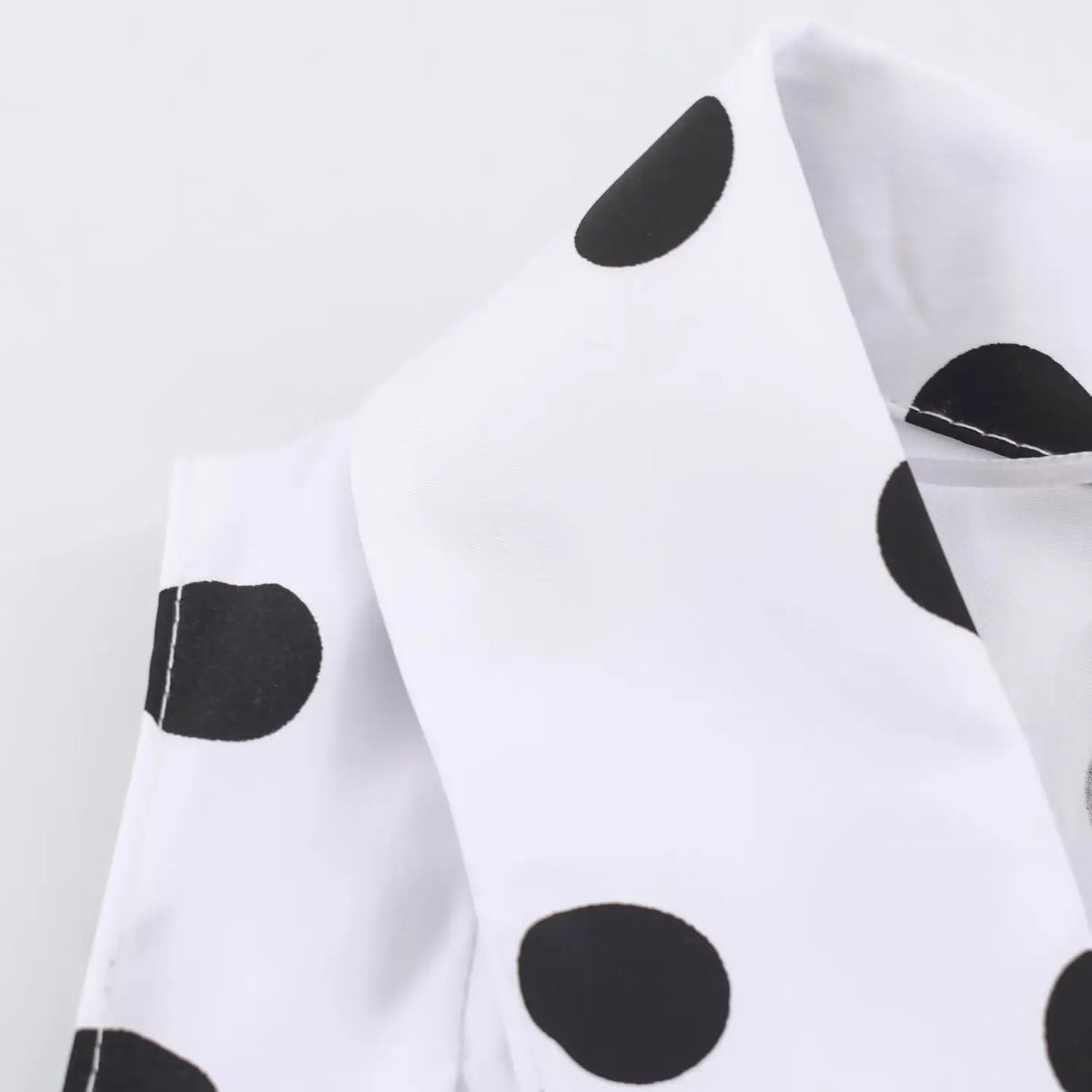 Close‑up lapel collar fabric detail on white black polka dot maxi dress