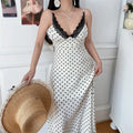 Model front shot white black polka dot maxi dress black lace v‑neck trim thin spaghetti straps fitted waist flowy long skirt