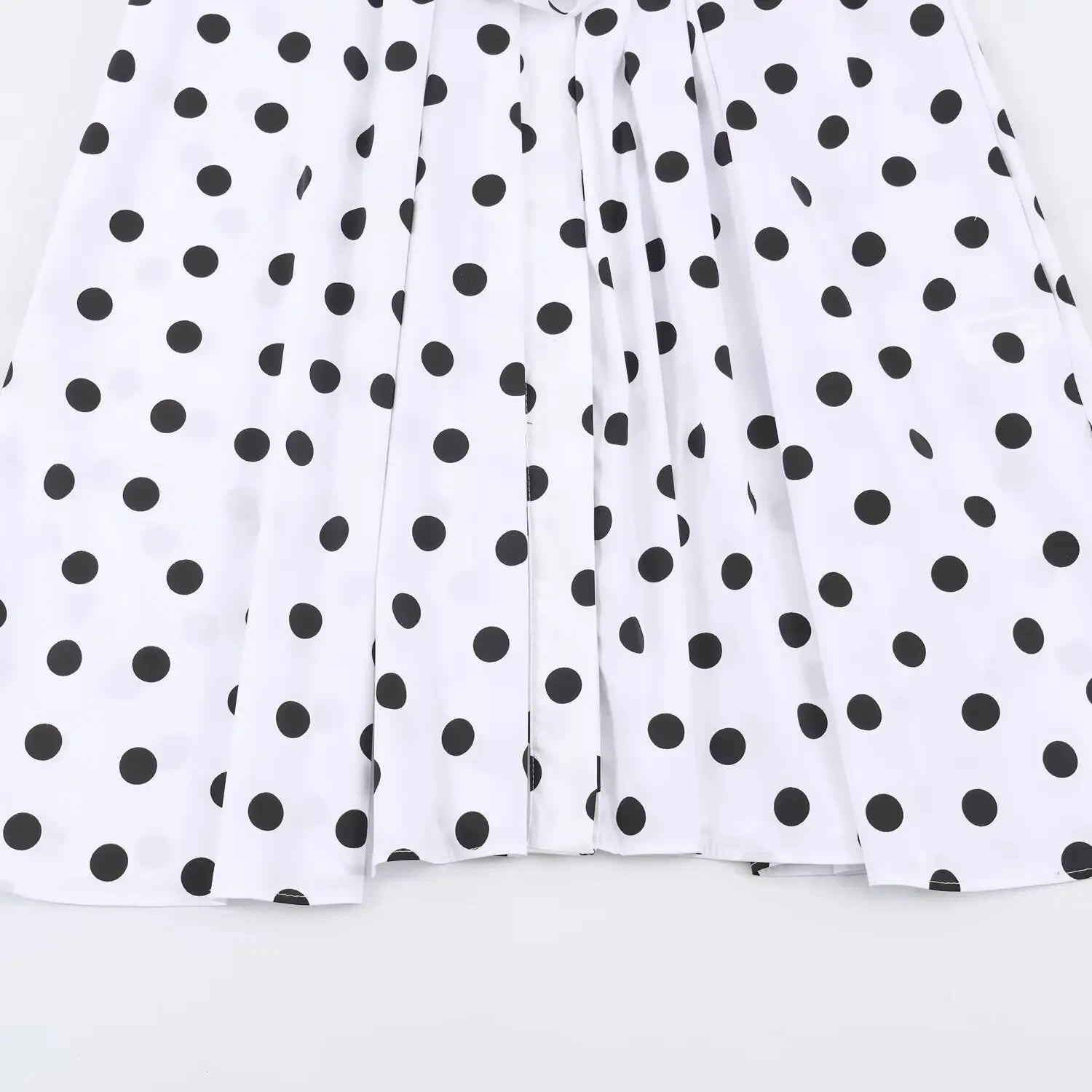 Close‑up view of skirt hem and pleats on white black polka dot sleeveless maxi dress