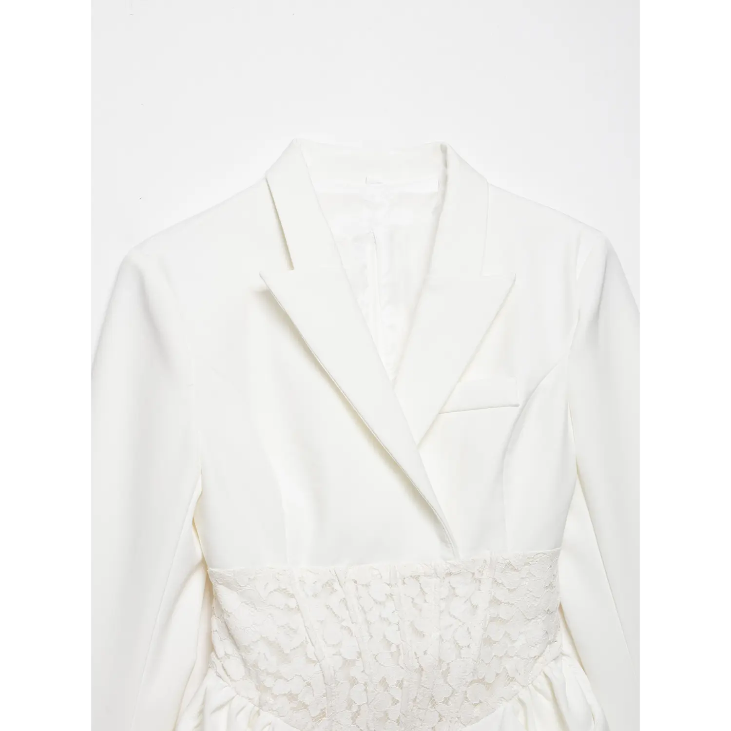 Close up shot of white blazer dress upper part, showing lapel collar and floral lace corset waist panel