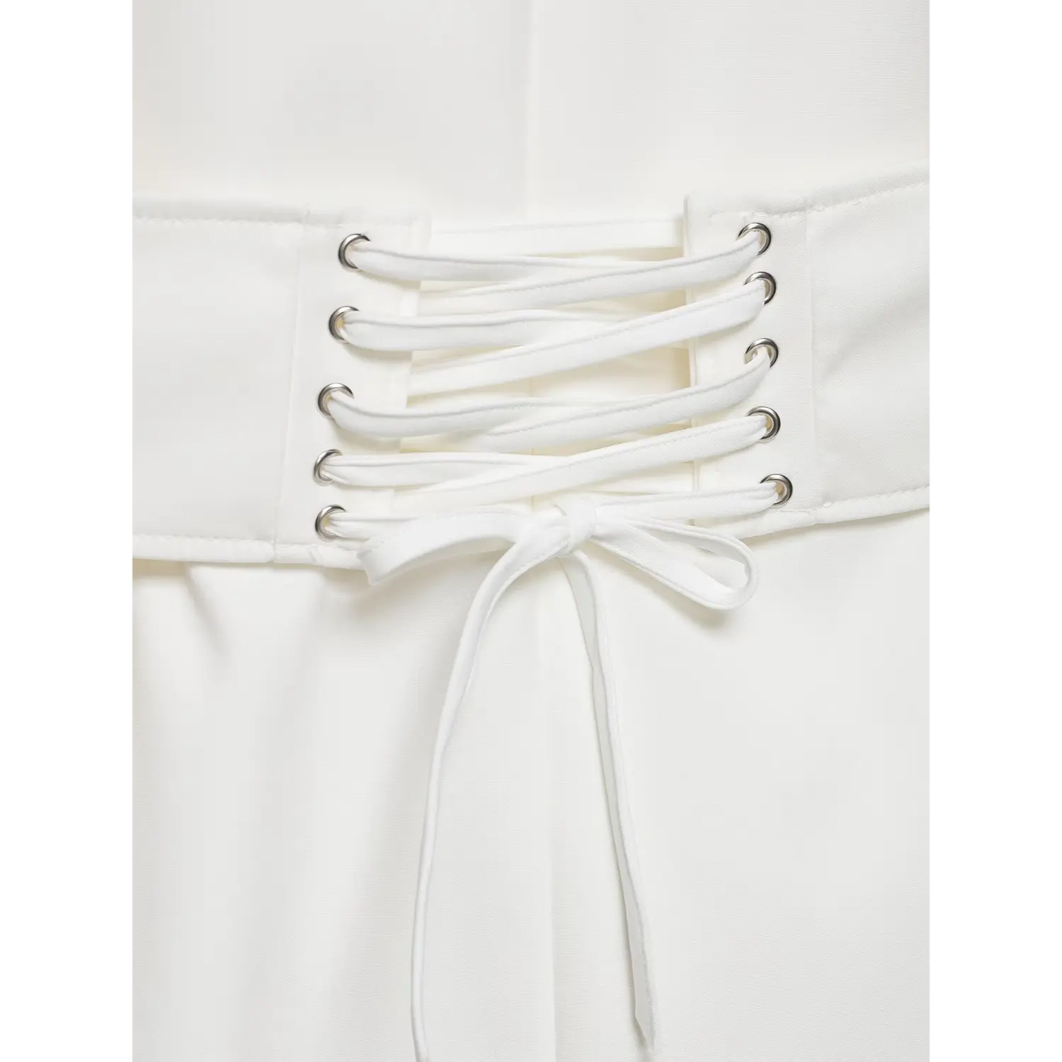 Macro detail of back lace-up corset belt, silver eyelets and fabric tie bow on white blazer dress